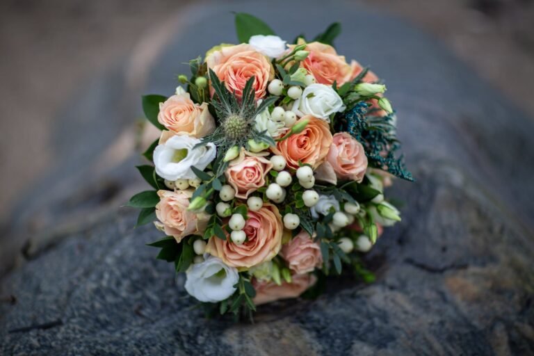 Delicate bridal bouquet of peach and white roses with greenery, perfect for weddings.